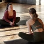 Two women practicing yoga indoors, embracing diversity and wellness.