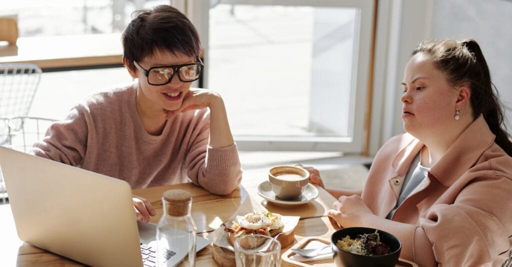 Two friends sharing breakfast and coffee at a cozy cafe, relaxed and happy.
