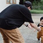 Joyful father and son bonding while playing outside their home. Capturing family happiness.