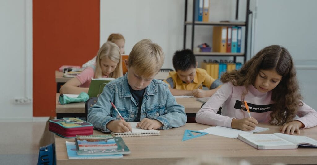 A group of children studiously engaged in writing and learning in a vibrant classroom setting.