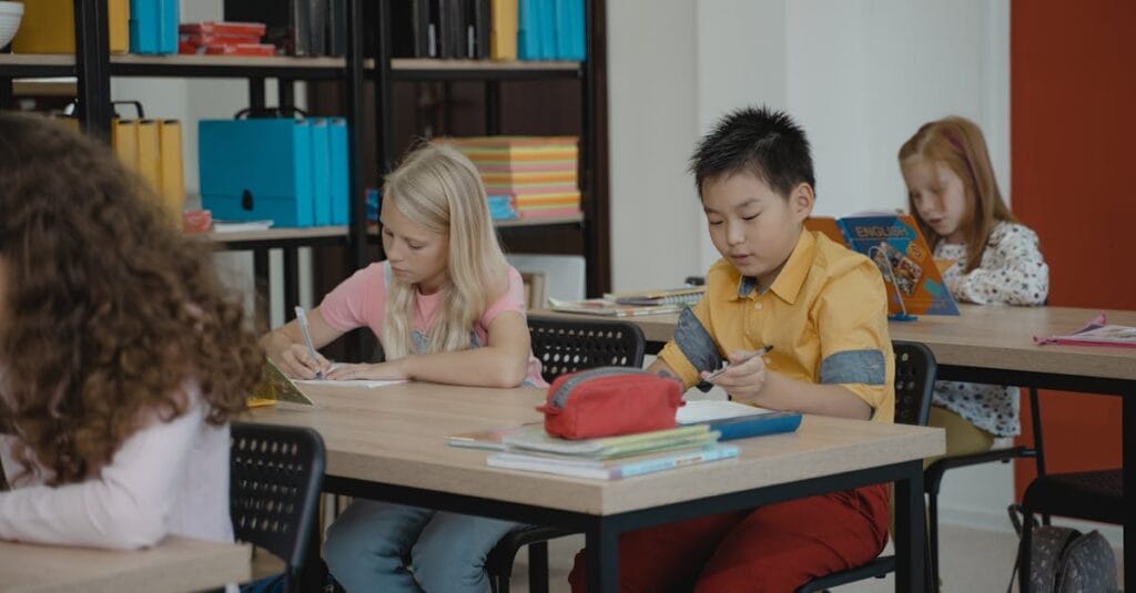 Children in a classroom setting, focusing on reading and writing activities.