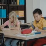 Children in a classroom setting, focusing on reading and writing activities.