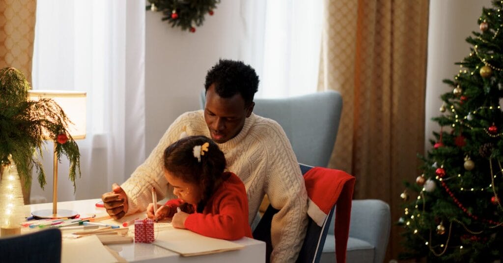 Father and daughter engaged in creative crafts during Christmas at home.