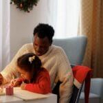 Father and daughter engaged in creative crafts during Christmas at home.