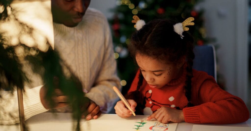 A father and daughter bond over drawing Christmas crafts indoors, capturing holiday spirit and family togetherness.
