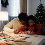A heartwarming scene of father and daughter crafting together during Christmastime indoors.