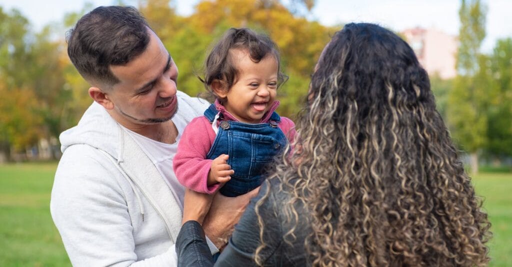 Smiling parents with a joyful child enjoying a day at the park, embracing family bonds.
