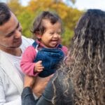 Smiling parents with a joyful child enjoying a day at the park, embracing family bonds.