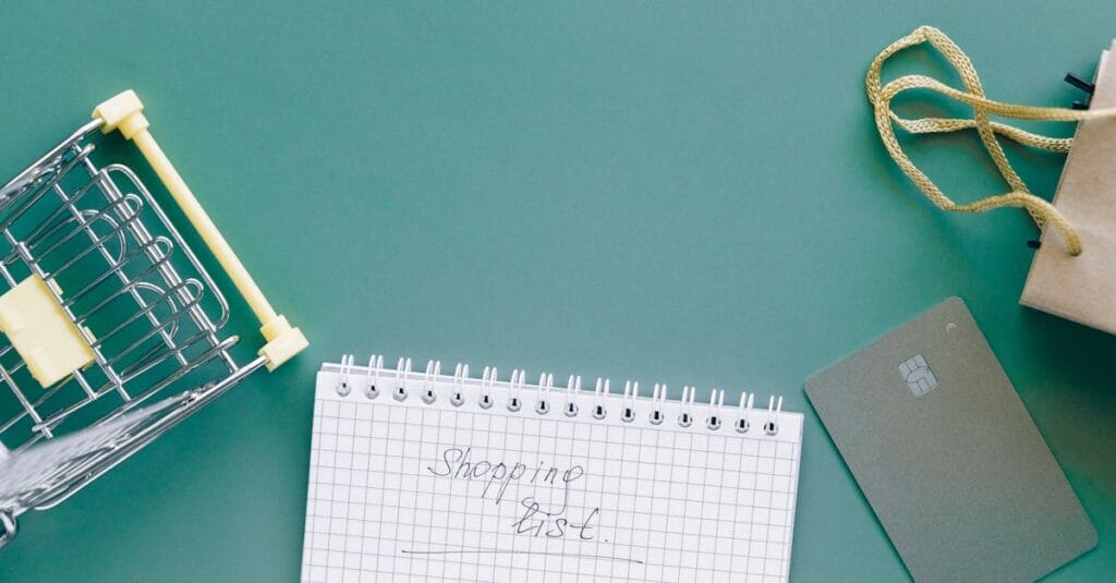 A top-down view of a shopping cart, list, card, and bag on a green background.
