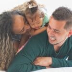 A joyful family bonding on a bed at home, capturing love and happiness.