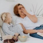 A joyful moment of a mother and child sharing laughs while reading together indoors.