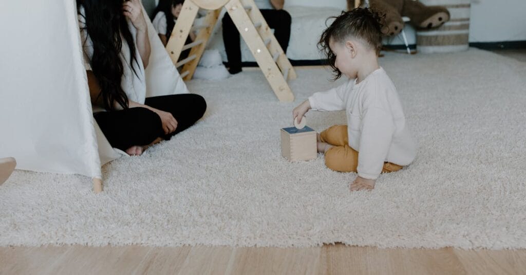 A mother and child enjoying playtime on a carpeted floor with toys.