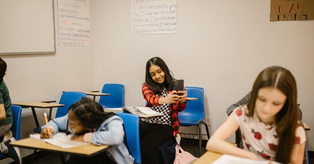 A diverse group of students in a classroom setting, one using a smartphone.