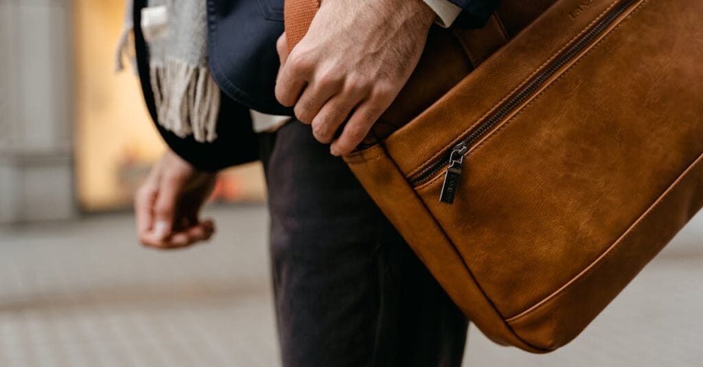 A fashionable man carrying a brown leather bag hints at modern business travel.