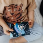 A young child sits on the floor assembling a space-themed puzzle piece.