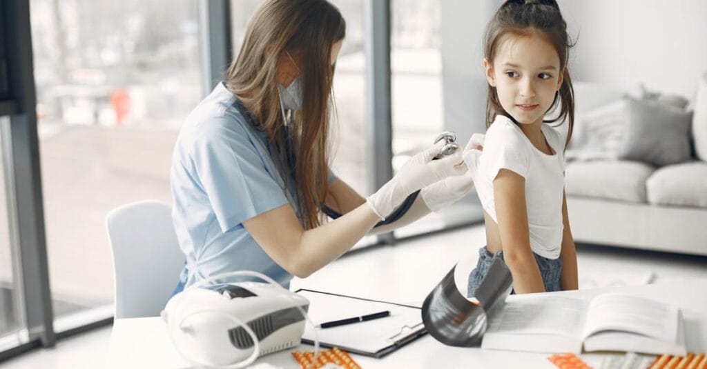 Young girl in clinic receiving a checkup from a female doctor with stethoscope.