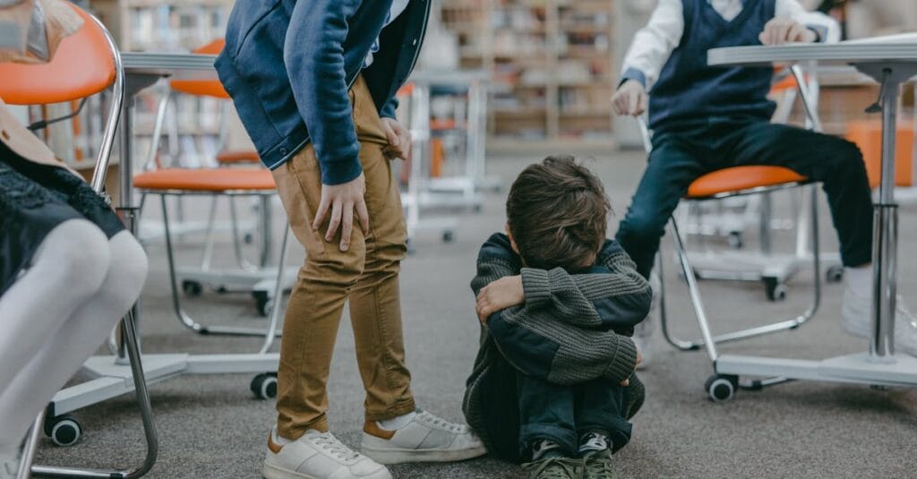 A young child sitting on the floor in a classroom facing bullying from peers.