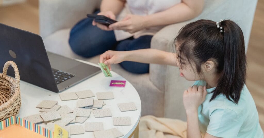 Asian girl focused on memory game at home with cards, enhancing cognitive skills.