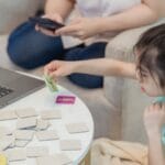 Asian girl focused on memory game at home with cards, enhancing cognitive skills.