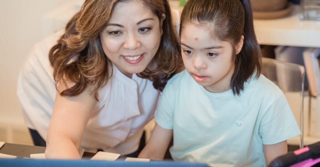 A woman and young girl using a computer together, showcasing family bonding and technology learning.
