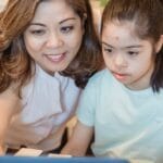 A woman and young girl using a computer together, showcasing family bonding and technology learning.