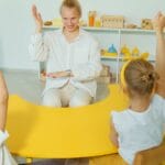 A lively preschool class with children participating in a learning activity guided by a cheerful teacher.