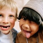 Two joyful children taking a fun selfie, capturing their silly expressions indoors.