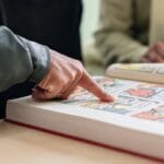 Two individuals focus on reading a colorful comic book, highlighting engaging stories.