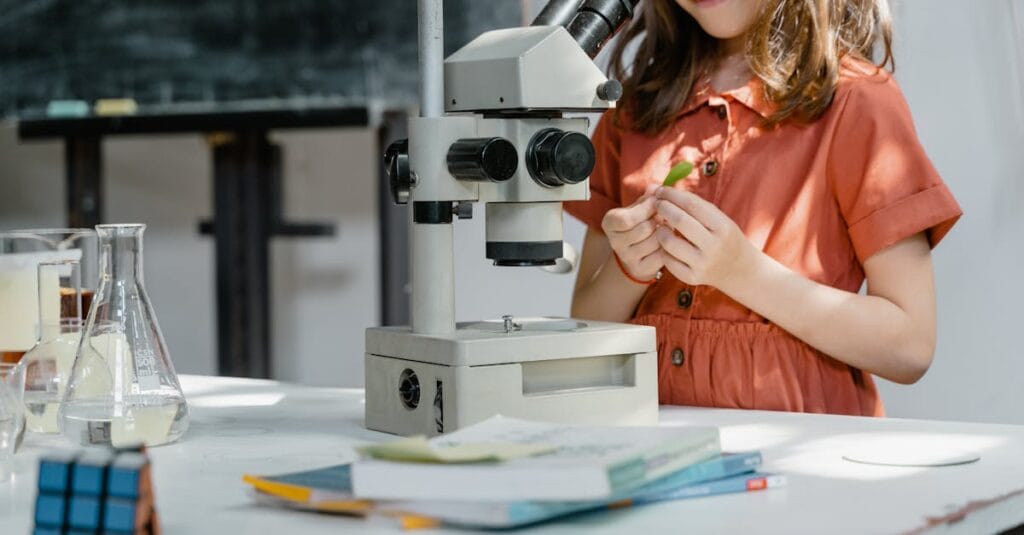 Young girl exploring science with a microscope and lab equipment indoors.