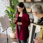 A student and teacher engaged in a music lesson with an accordion indoors.