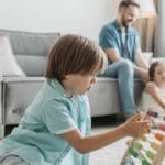 A boy playing with an abacus while family enjoys time together in a cozy living room.