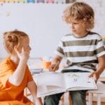 Two children engaged in reading and learning indoors at school.