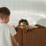 Mother and son playing hide and seek with dinosaur toys indoors. Captures playful family bonding moments.