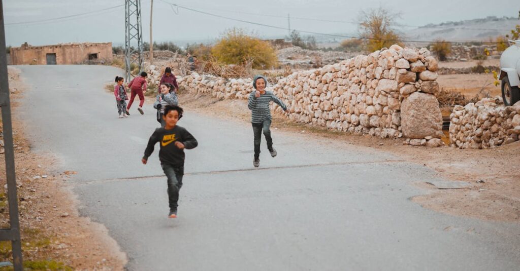 Group of kids running and playing on a rural street under a cloudy sky.
