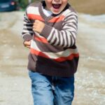 A young boy joyfully runs down a path, showcasing playful energy in a Czech outdoor setting.