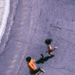 Aerial shot of children running on a city street crosswalk, creating a dynamic and energetic scene.