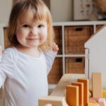 Adorable toddler joyfully playing with toys in a cozy indoor playroom, enjoying fun and happiness.