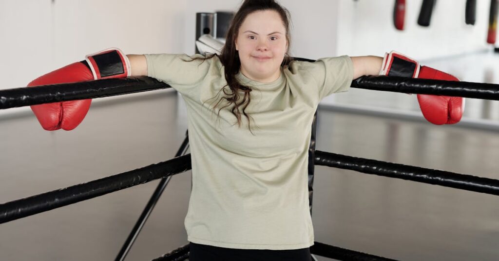 Young woman with Down syndrome wearing boxing gloves, smiling confidently in the gym.