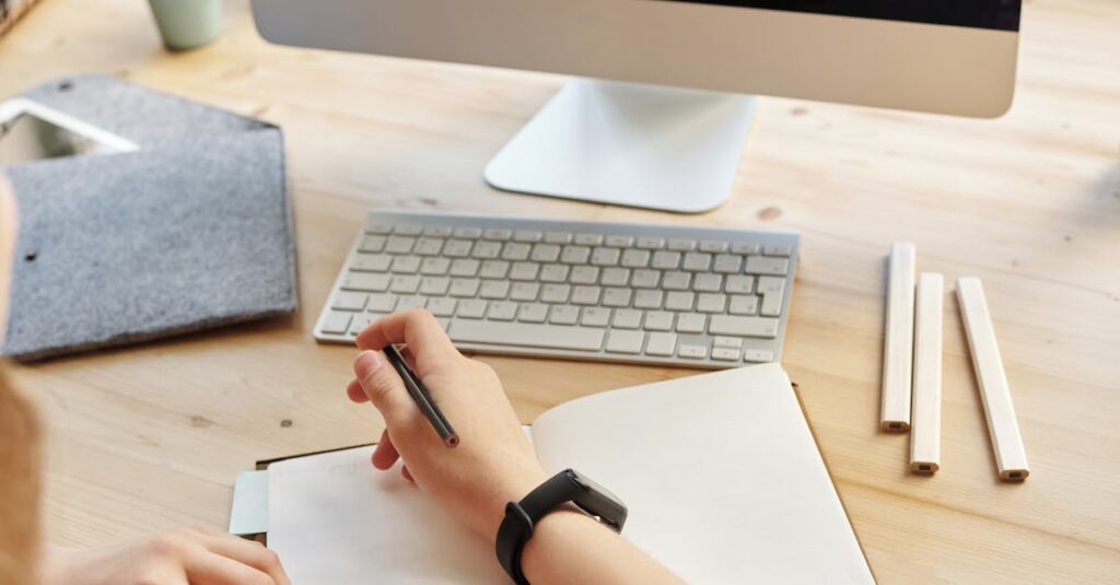 Student attending virtual class on a computer, taking notes at home.