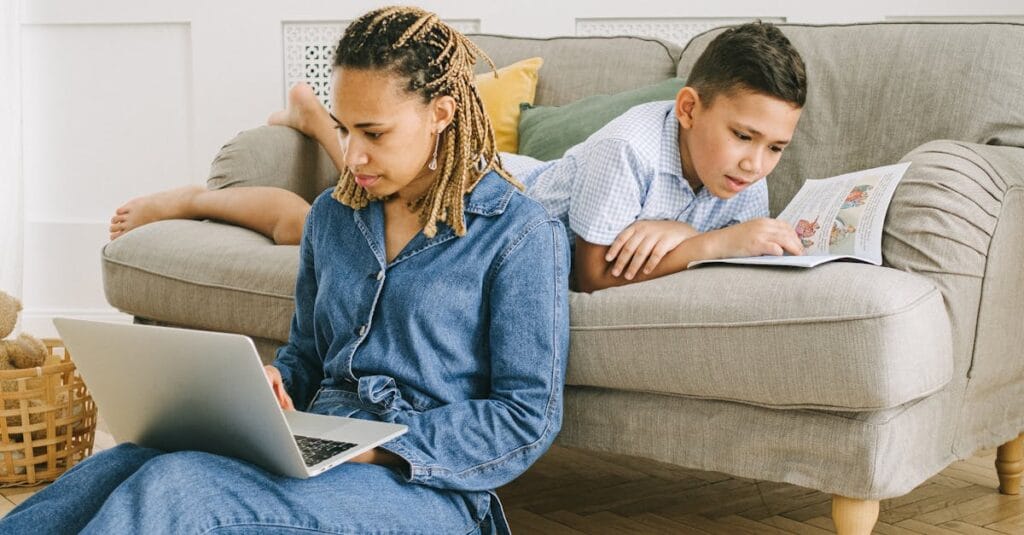 A mother and son enjoying leisure activities indoors with a laptop and book.