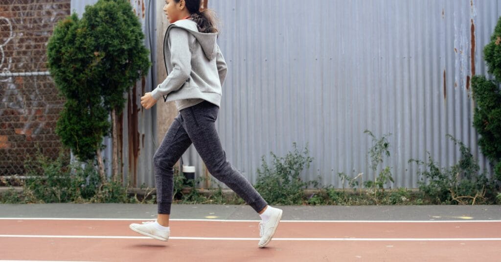A girl in activewear jogging on an outdoor track, showcasing a healthy lifestyle.