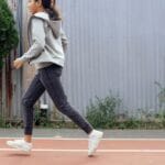 A girl in activewear jogging on an outdoor track, showcasing a healthy lifestyle.