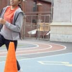 Full body of active Hispanic schoolgirl in sportswear running while having physical education class