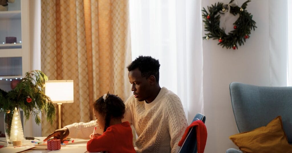 Father and daughter crafting together at home during the festive Christmas season with warm atmosphere.