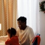 Father and daughter crafting together at home during the festive Christmas season with warm atmosphere.