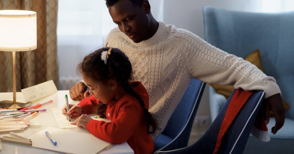 Father and daughter enjoying creative bonding time while writing a Christmas letter.