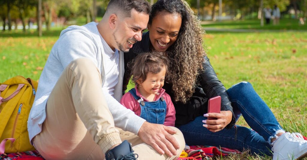 A happy family of three taking a selfie outdoors on a sunny day in the park.