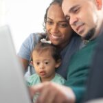 A happy family bonding while using a laptop together in a cozy indoor setting.