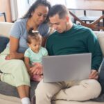 A family spending quality time together on a sofa, engaging with a laptop.