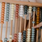A child playing with a colorful wooden abacus, focusing on math learning and development.